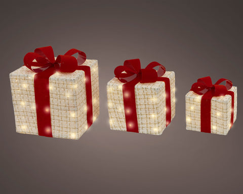 Drei weiße led geschenkschachteln mit warmweißen led leuchten und rotem band aus gewebtem beigem muster