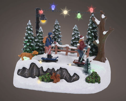 Led-winterszene langlauf diorama mit mini-skifahrern, hund, kiefern und leuchtenden lichtern auf schneebasis