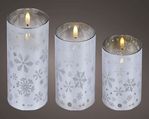 Set aus drei weißen zylindrischen led-kerzenhaltern mit silbernen schneeflocken- und sternmustern
