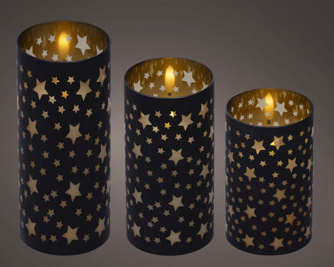Set aus drei schwarzen led kerzenhaltern aus zylinderform mit goldenen sternausschnitten und leuchtendem innenraum