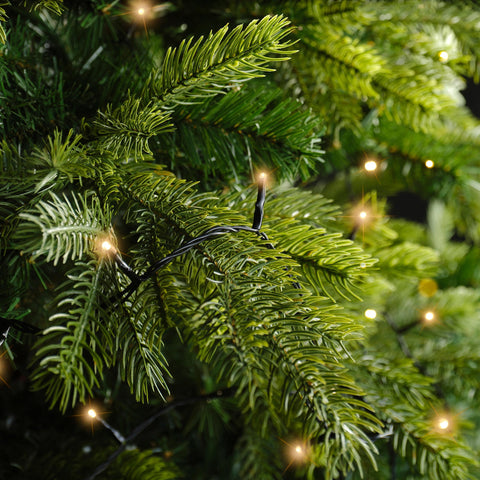 String aus warmweißen led weihnachtsbaumlichtern mit 120 leds 9m lang zwischen grünen kiefernzweigen