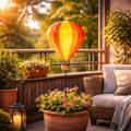 Metall gartenstecker heißluftballon gelb-orange mit leuchtendem korb aus geflochtenem metall über blumenkübel
