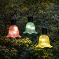 Drei bunte solar gartenleuchten solar blume 10x7.5cm in gelb, türkis und rosa mit geripptem glas hängen an zweigen