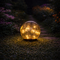 Solar-lampe 10cm mit goldenen lichterketten in klarer glaskugel auf dunklem sockel
