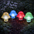 Vier bunte pilz solar-lampen mit durchscheinender kuppel und weißen punkten aus kunststoff im garten