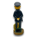 Solar-erdmännchen polizist figur 30cm in dunkelblauer uniform mit schwarzer mütze und goldenen handschuhen auf holzsockel neben grünem laub