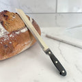 Xxl brotmesser 33cm schwarzer griff serriertes edelstahlmesser neben artisanalem sauerteigbrot