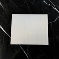Ein glattes, off-white wiederverwendbares dauerbackpapier aus teflon 40x33 cm auf dunkler marmoroberfläche
