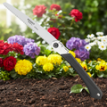 Klappsäge gfs01-l mit schwarzem griff und silberner klinge 270mm liegt auf boden vor bunten blumen