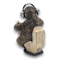 Detaillierte resin gartenfigur eines faultiers mit silbernen und schwarzen kopfhörern auf verwittertem beige wc sitz