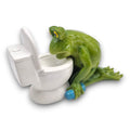 Grüne keramik froschfigur mit gelben augen hält blaue hantel und lehnt an weißem wc frosch vor dem wc 16,5x7,5x10cm