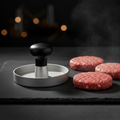 Silberne burgerpresse mit schwarzem griff zum plattdrücken roher fleischpattys