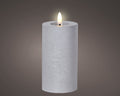 Eine weiße texturierte zylindrische led kerze aus wachs mit leuchtender flamme für dauerbetrieb indoor