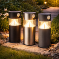 Premium solar-gartenleuchte mit bewegungssensor drei zylindrische leuchten metallisch und schwarz mit warmweißer led-beleuchtung