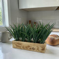 Ein rechteckiger holzkasten mit natürlicher holzmaserung und künstlichem grünem gras für kunstgras im holzkasten
