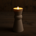 Ein cremefarbener gerippter keramik kerzenhalter outdoor-kerze 3d docht 8x8x17,5cm sand mit brennender flamme