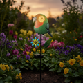 Grüne und orange papageienförmige solar gartenstecker mit leuchtendem auge auf schwarzem stecker mit blauem blütenornament