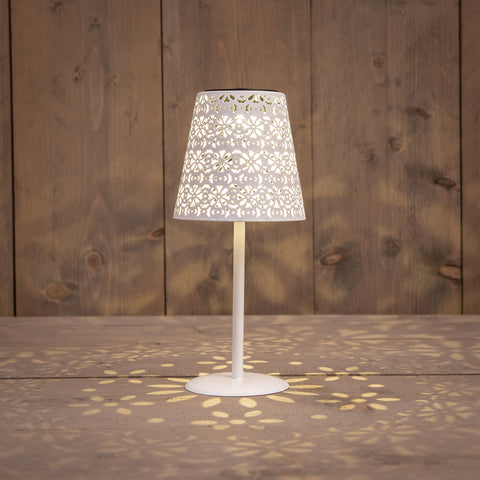 Solar tischlampe metall antikweiss mit floraler aussparung im schirm und lichtmustern auf holzoberfläche