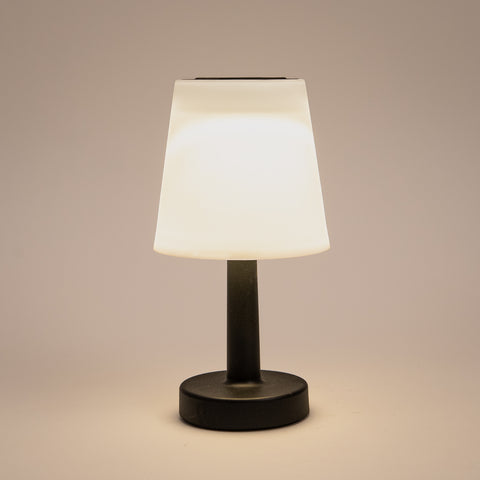 Eine elegante schwarze solar tischlampe mit einem mattweißen, konisch zulaufenden schirm und warmweißer led-beleuchtung