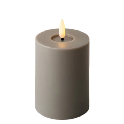 Eine matte graue zylindrische led kerze aus plastik mit warmgelbem flacker-effekt für den außenbereich