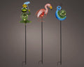Set aus drei bunten solar-gartensteckern mit tiermuster grüne froschfigur mit schirm pinker flamingo blaue raupe
