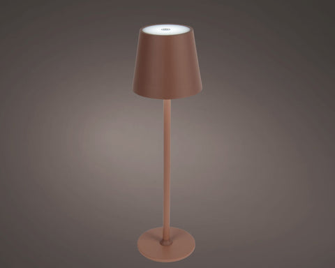 Ein kupferfarbener led wiederaufladbarer tischlampe mit zylinderschirm und schlankem gestell für den außenbereich