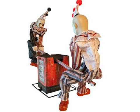Zwei unheimliche animatronik-clownfiguren in gestreiften kostümen und hohen hüten neben einer wetterfassaden holzkiste