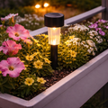 Schwarze solar-stick gartenleuchte mit klarem glasgehäuse und warmgelbem lichtschein