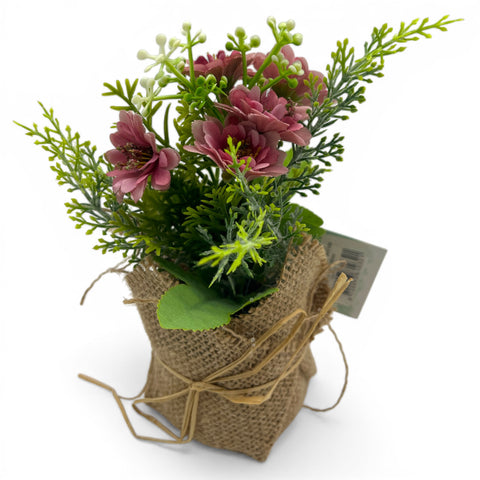 Ein charmantes künstliches blumenarrangement mit zarten rosa blüten in einem rustikalen jutesack