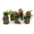Blume im jutesäckchen mit künstlichen blumenarrangements in pastell und kräftigen tönen, mit jute und schnur gebunden