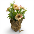 Ein zartes blumenbouquet aus creme und rosa künstlichen blumen mit grüner folie in einem jutesäckchen