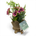 Blume im jutesäckchen mit künstlichen rosa und grünen blüten in rustikalem leinentopf