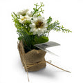Blume im Jutesäckchen mit weißen blüten und grüner folie in rustikalem burlap-topf
