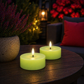 Zwei leuchtend limegrüne led-teelichter mit realistischem flammeneffekt auf holztisch solarkerze grün 7x7x3,2cm