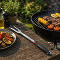 Silberne genius grill gabel aus metall mit schwarzem und rotem ergonomischem griff auf holztisch