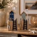 Zwei miniatur holzfigur häuschen in marineblau und salbeigrün mit weißen flaggenmasten und fischdekorationen