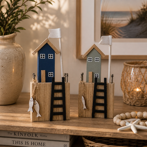 Zwei miniatur holzfigur häuschen in marineblau und salbeigrün mit weißen flaggenmasten und fischdekorationen