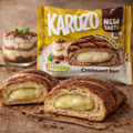Ein goldenbraunes, blättriges karuzo gefülltes croissant 82 g mit cremiger gelber füllung und kakao bestäubt