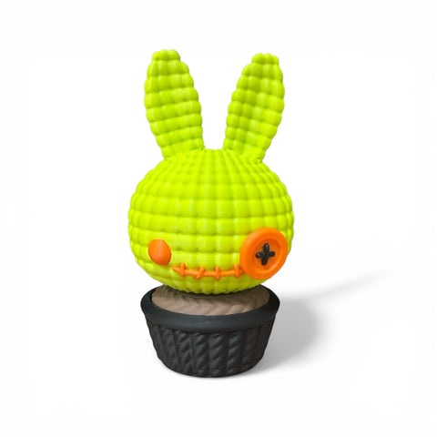 3d voodoo-hase hellgrüner gehäkelter hase mit orangen knopfachsen sitzt in schwarzem strukturiertem topf
