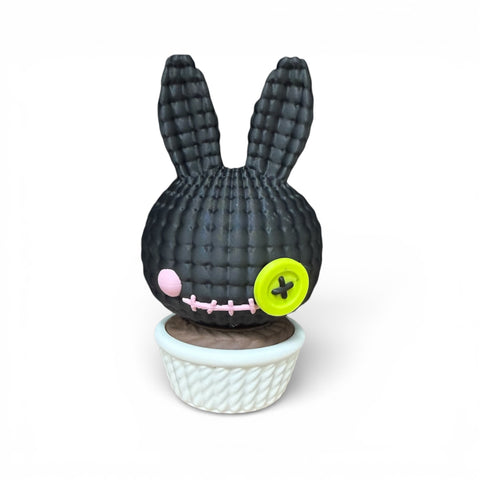 3d voodoo-hase schwarze gestickte hasenfigur mit limegrünem knopfauge und rosa wange im weißen geflochtenen topf