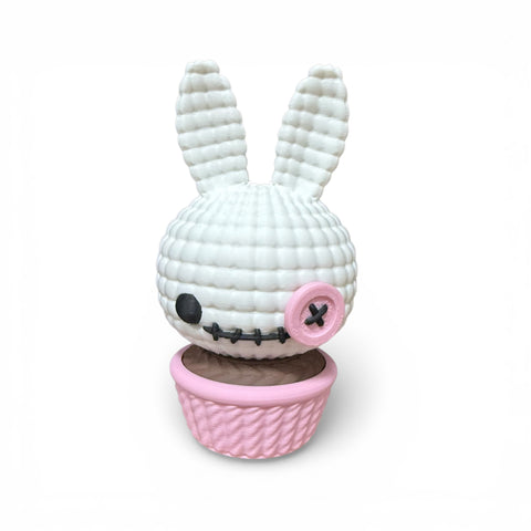 Weißer gehäkelter 3d voodoo-hase mit rosa knopfachse und gesticktem mund sitzend im passenden rosa korb