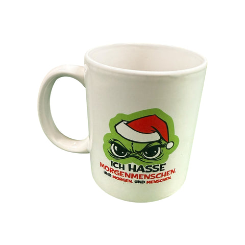 Weiße keramiktasse mit grünem cartoon-charakter und rotem weihnachtshut mit text ich hasse morgenmenschen