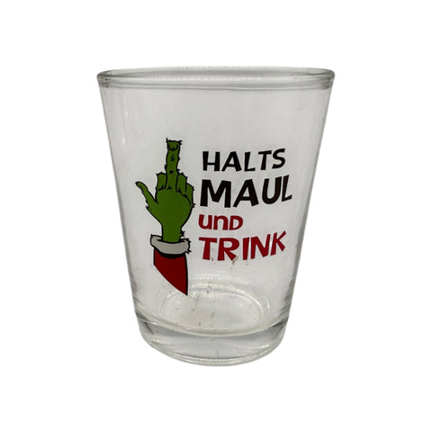Klarer glas schnapsglas mit grünem grinch hand zeigend den mittelfinger und schwarzem roten text festtagsmuffel