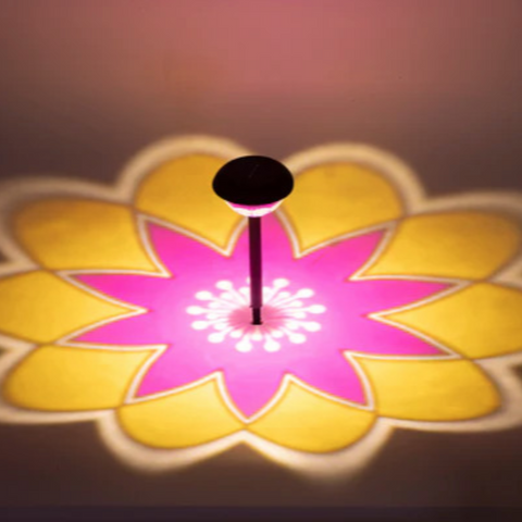 Schwarze solar-gartenlampe mit 360° muster wirft pink-gelbe blumen-schattierungen auf den boden