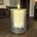 Eine leuchtende weiße led kerze tar 3d 7x10cm in einem klaren zylindrischen glasbehälter