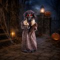 Eine 95 cm große puppe mit drehendem kopf als gruselige halloween-animatronik in staubigem lila kapuzenkleid mit leuchtend roten augen und blondem haar hält ein stofftier