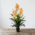 Künstliche cymbidium orchidee mit orange-gelben blüten und grünen blättern in schwarzem topf 40x40x150cm