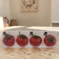 Roter tischdeckengewicht tomate aus metall mit grünem stiel und clipverschluss zum befestigen an taschen oder kleidung