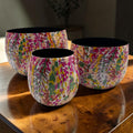 Set aus drei rundem keramik Übertopf metall mit floralen Mustern in pink gelb grün und lila innen schwarz
