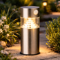 Premium solar-gartenleuchte mit bewegungssensor in gebürstetem edelstahl mit klarer glasfassung und warmweißen led